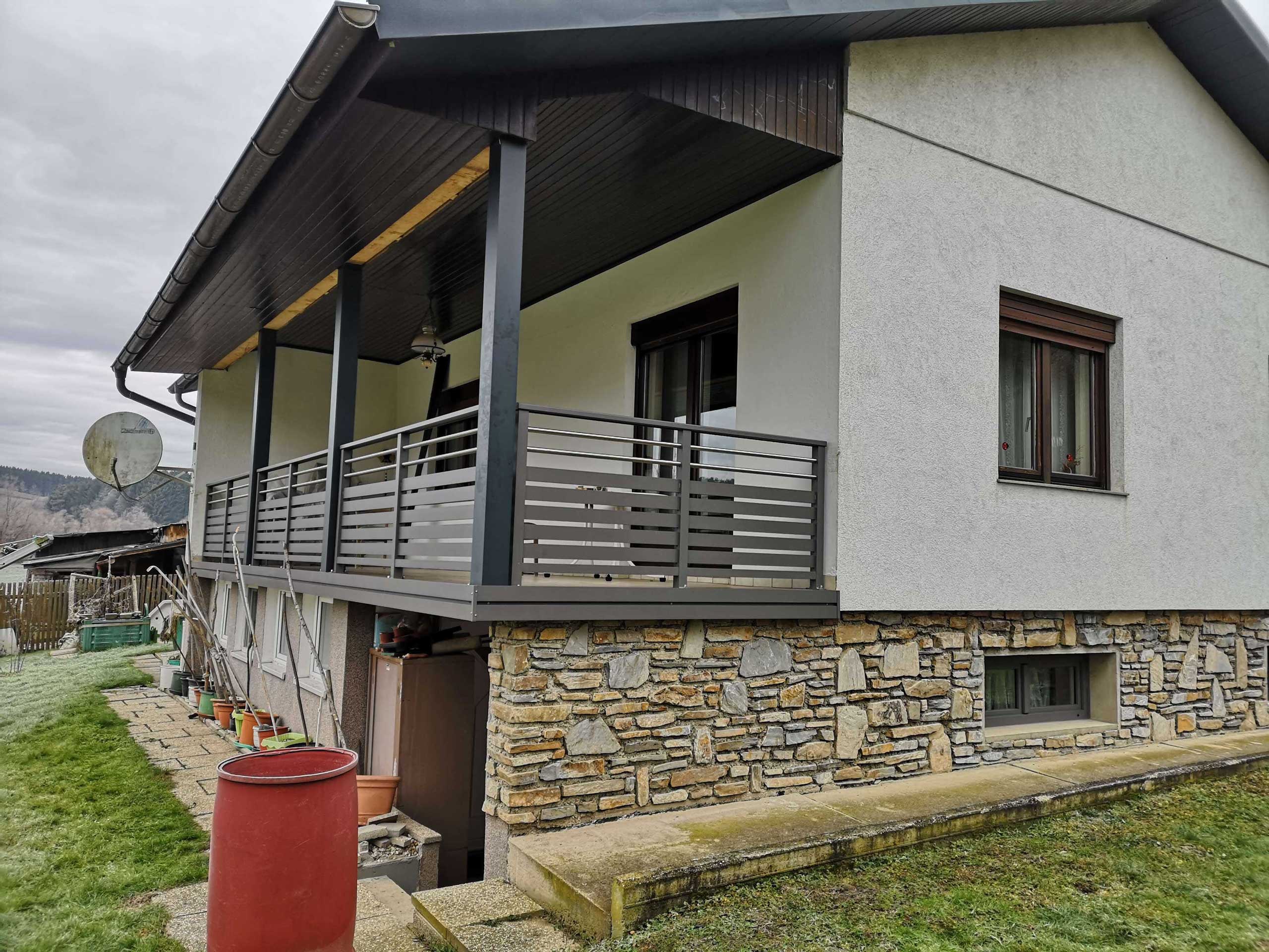 Dunkelgrauer Alubalkon an einem grauen Haus