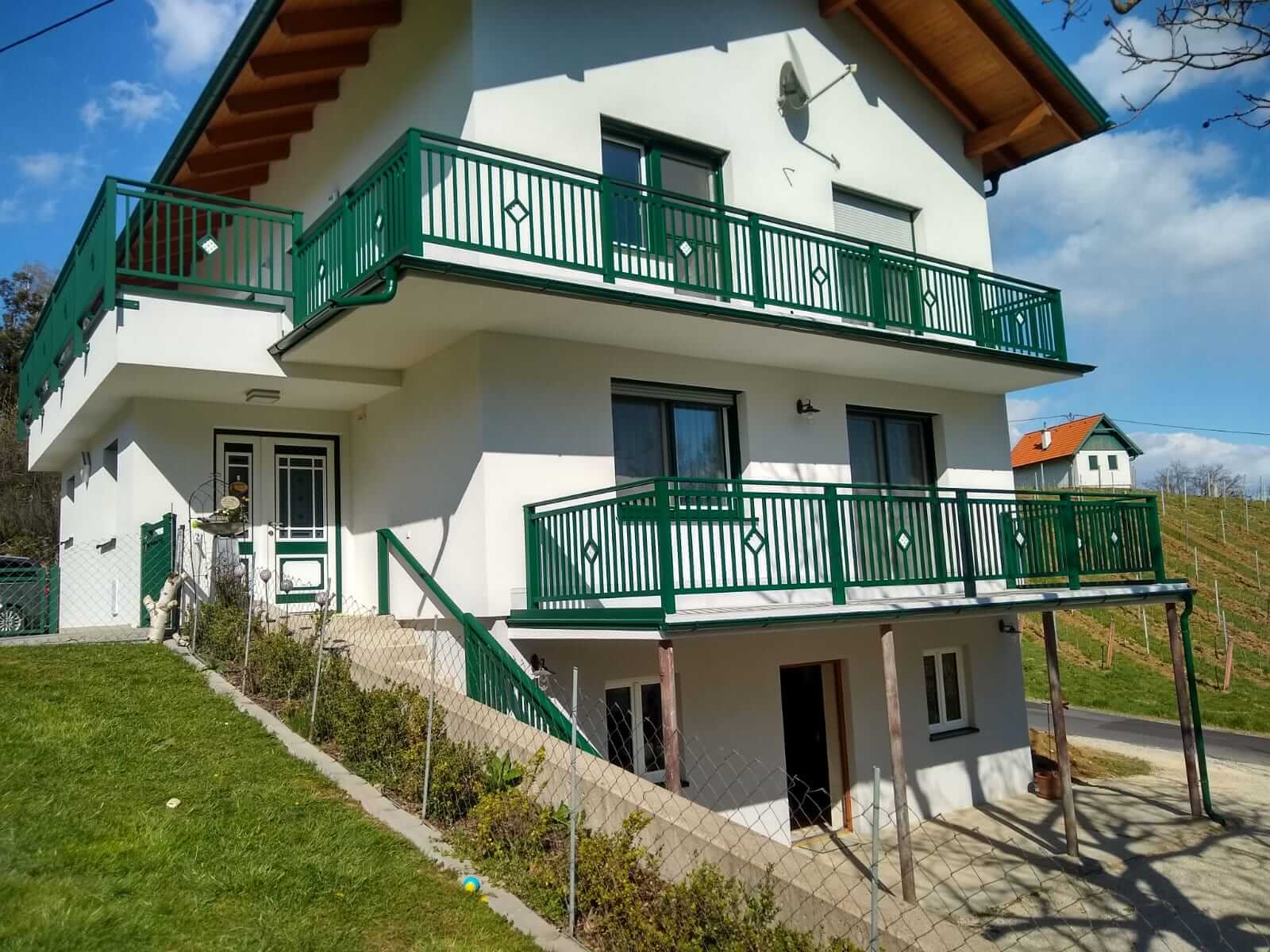Grünber Alubalkon an einem weißen Haus