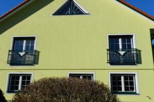 Grüner Aluzaun an einem gelben Haus