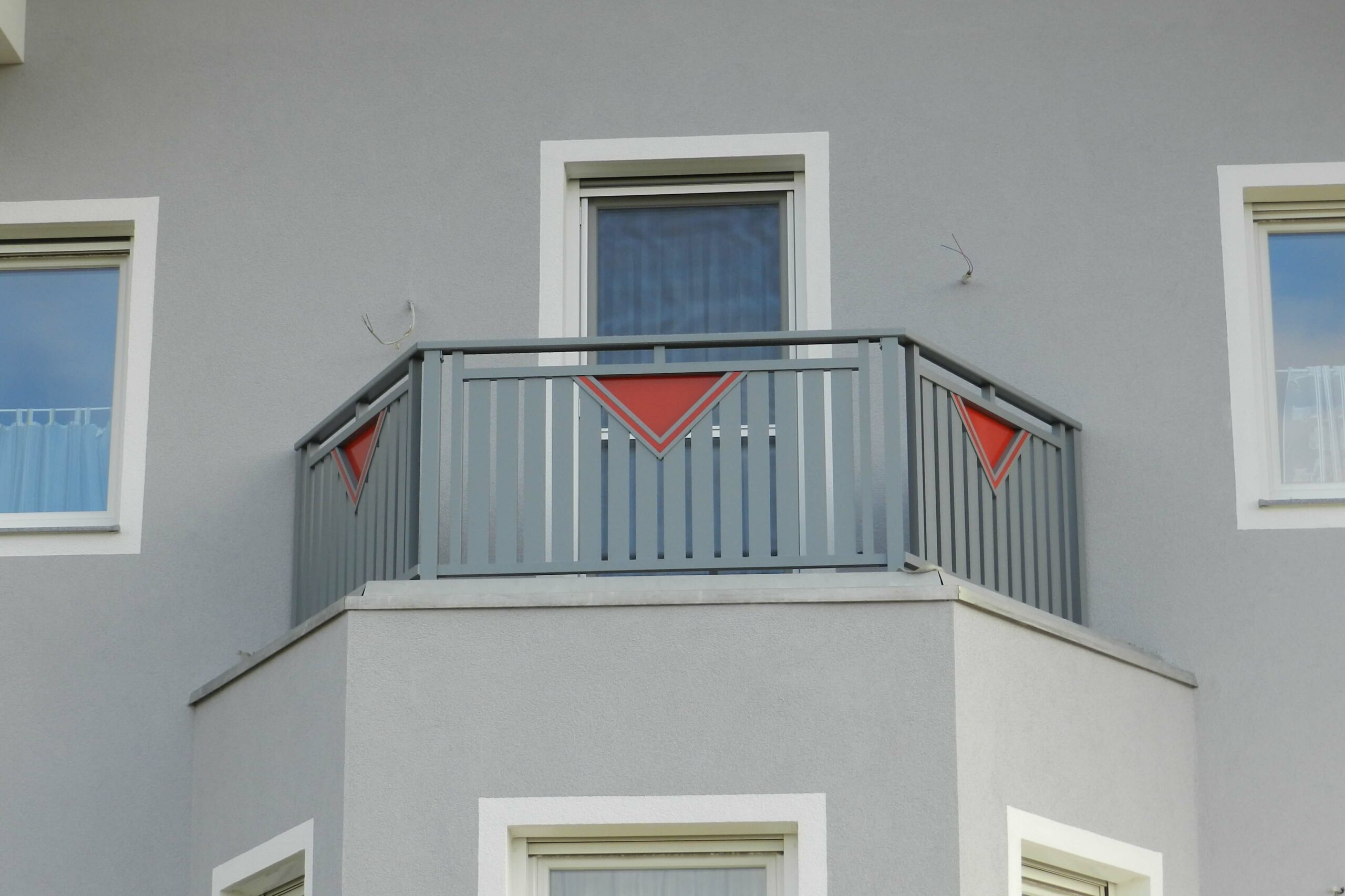 Grauer Alubalkon mit roten Elementen