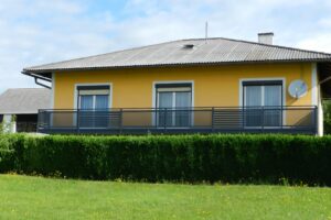 Dunkelgrauer Alubalkon an einem gelben Haus