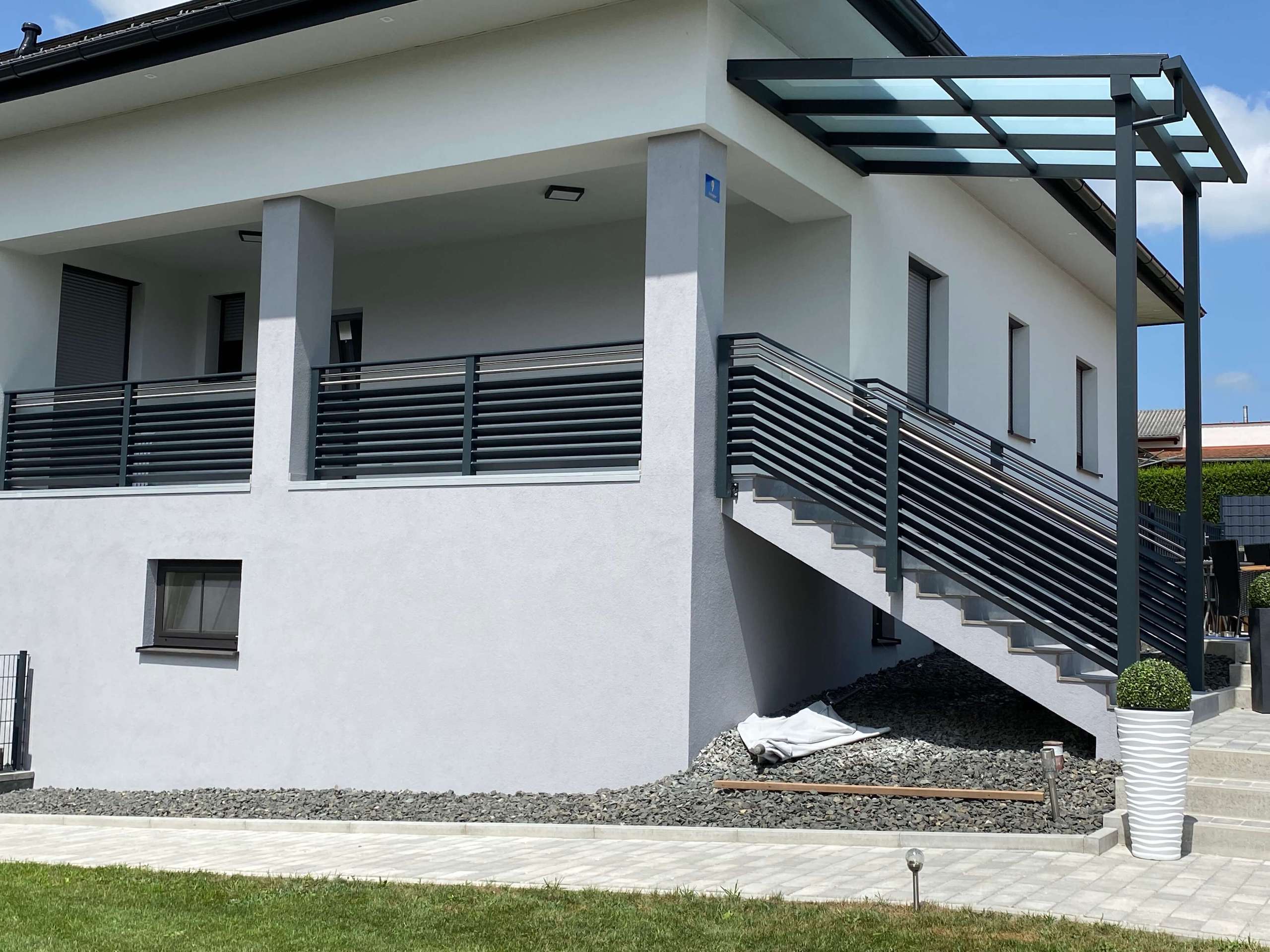 Grauer Alubalkon am Hauseingang eines weißen Hauses