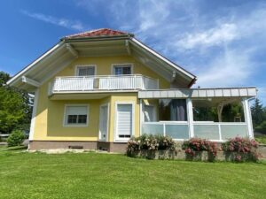 Weißer Alubalkon an einem gelben Haus