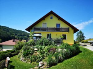 Grauer Aluzaun und -balkon an einem gelben Haus