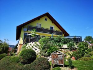 Grauer Aluzaun und -balkon an einem gelben Haus