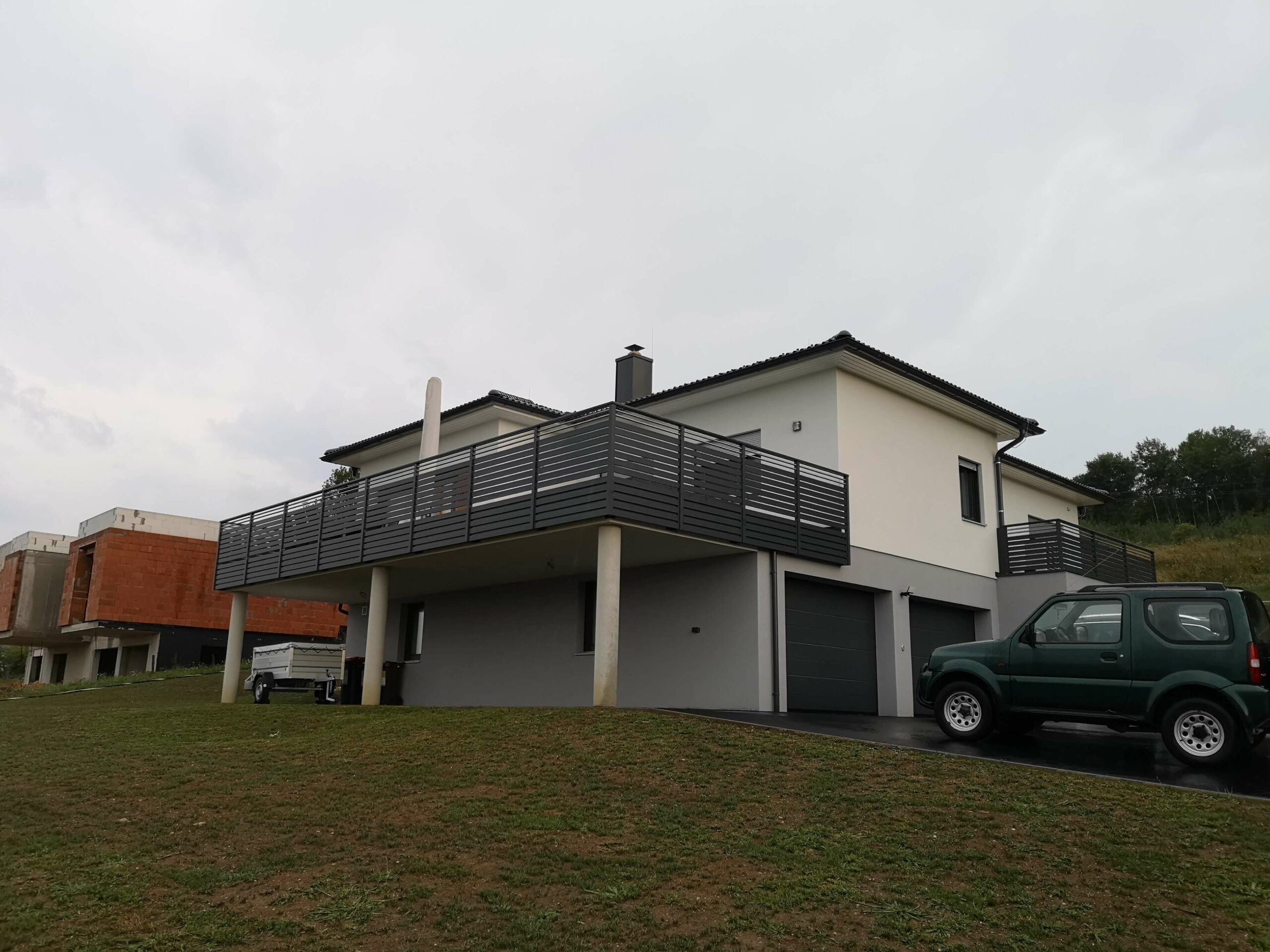 Grauer Alubalkon an einem weißen Haus