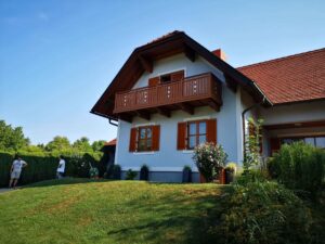 Brauer Aluzaun mit weißen Elementen an einem blauen Haus