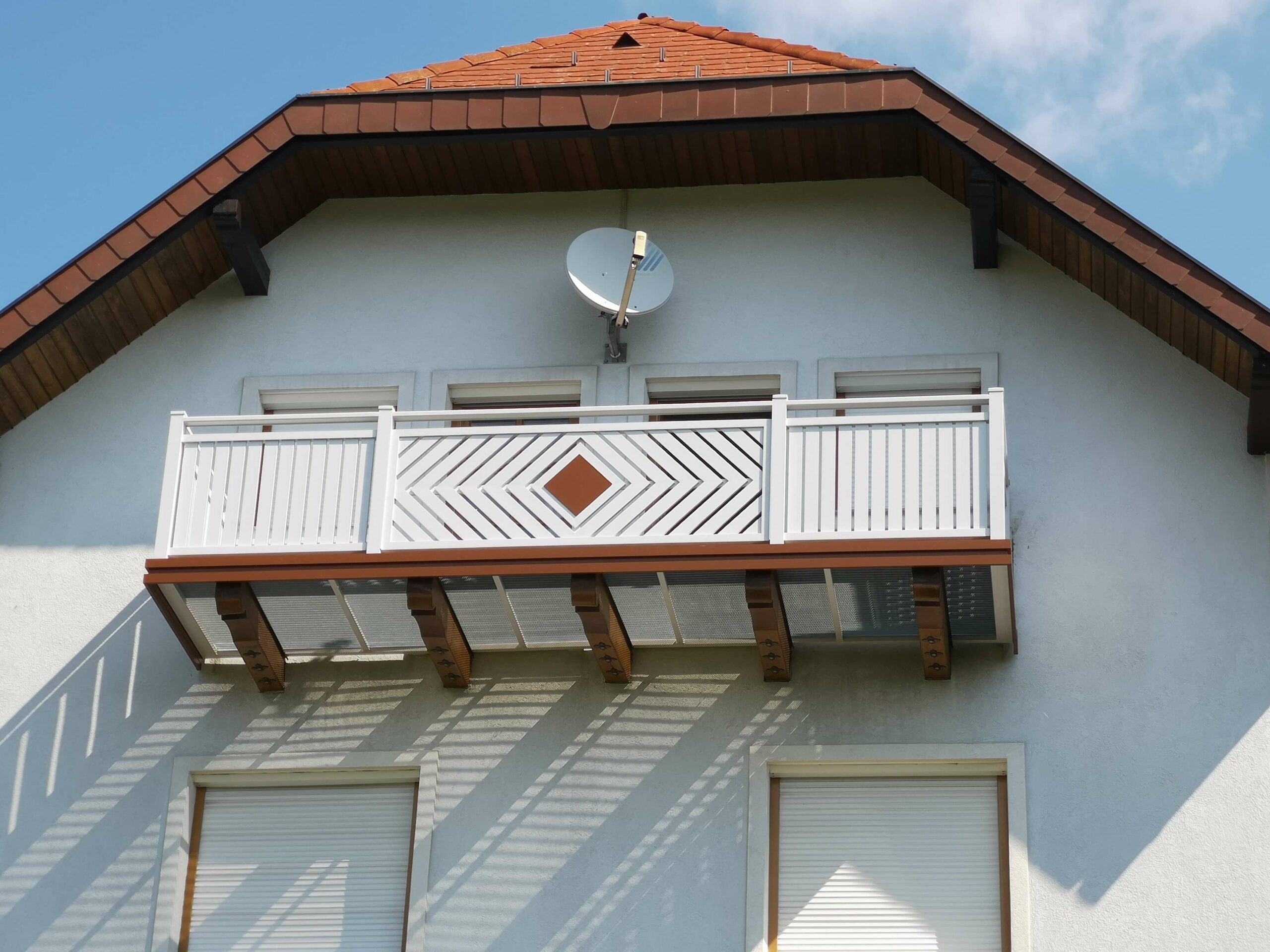 Weißer Aluzaun mit braunen Elementen an einem weißen Haus