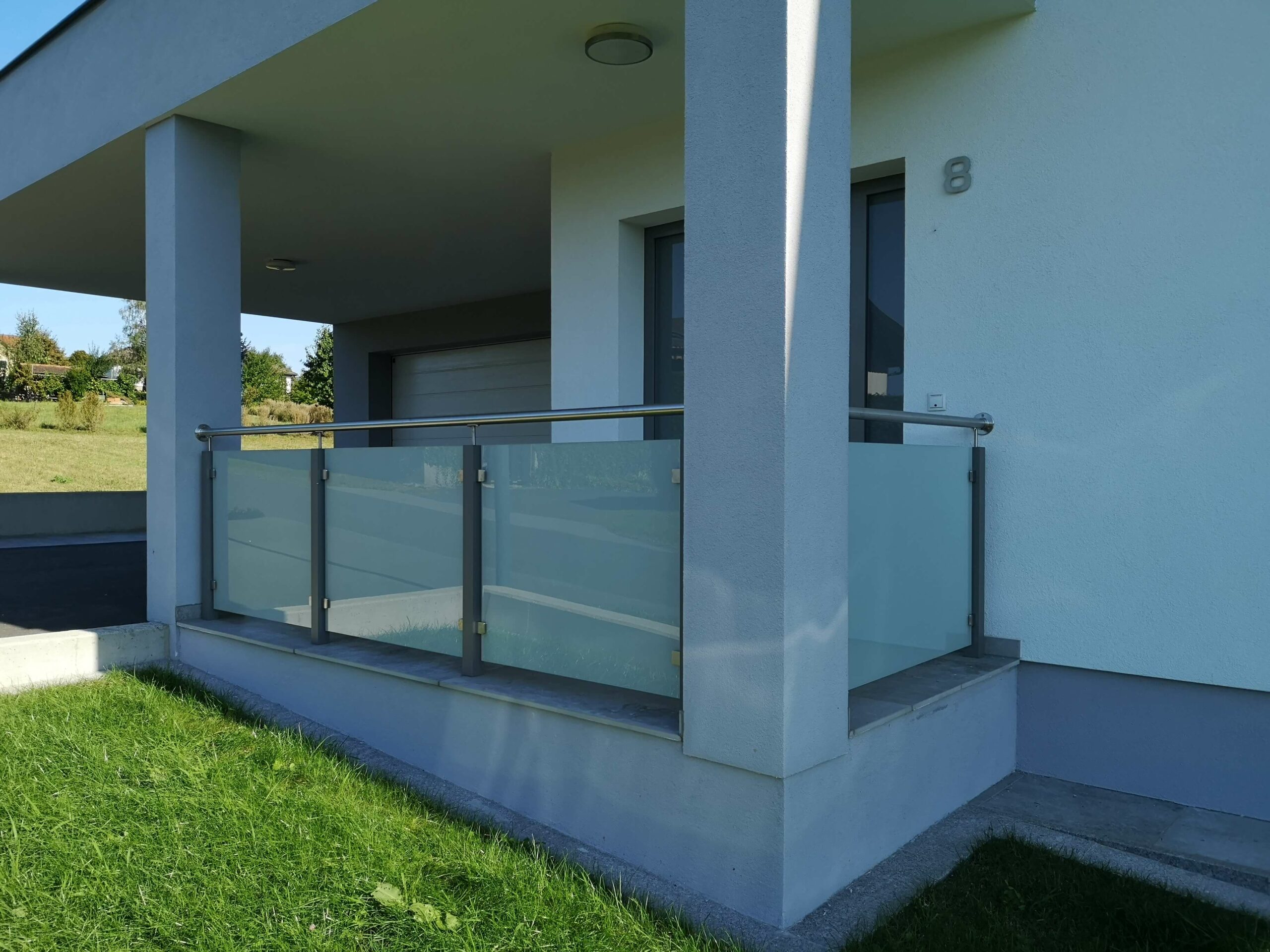 Silbener Aluzaun mit Glaseinsätzen bei einem Hauseingang