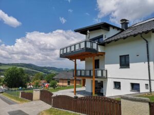 Grauer Alubalkon mit Glaselementen an einem weißen Haus