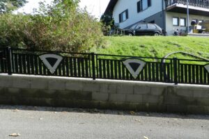 Grauer Aluzaun auf einer Steinmauer