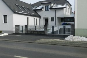 Grauer Aluzaun auf einer Steinmauer