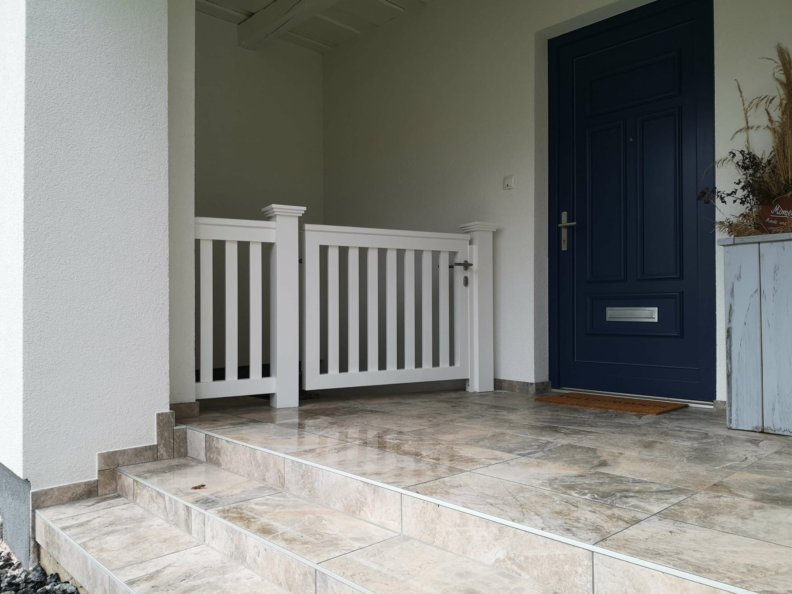 Weißes Alutor neben dem Hauseingang