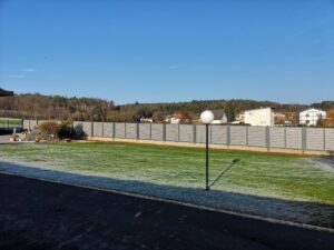 Grauer Aluzaun auf einer Mauer