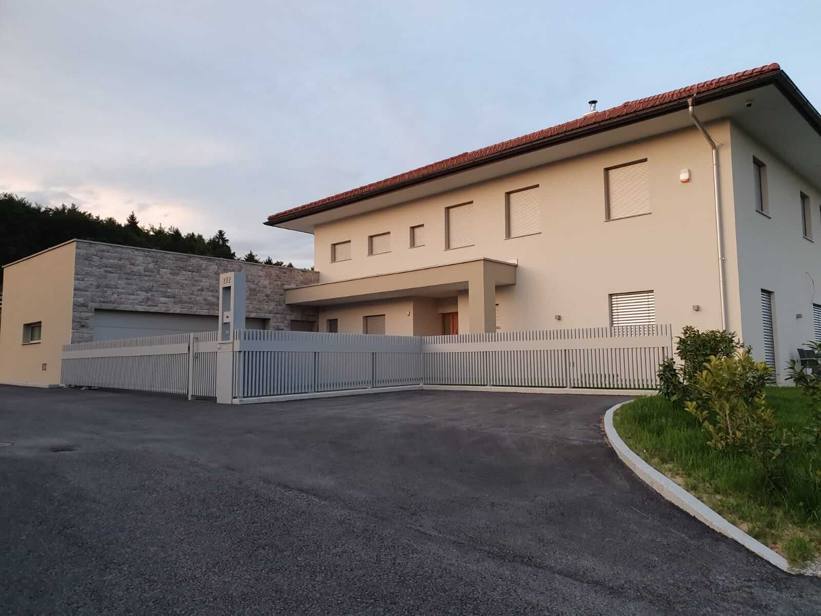 Weißer Aluzaun mit Tor bei einem beigen Haus