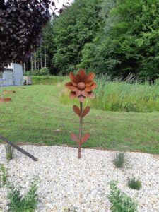 Braune Blume aus Metall vor einer Wiese