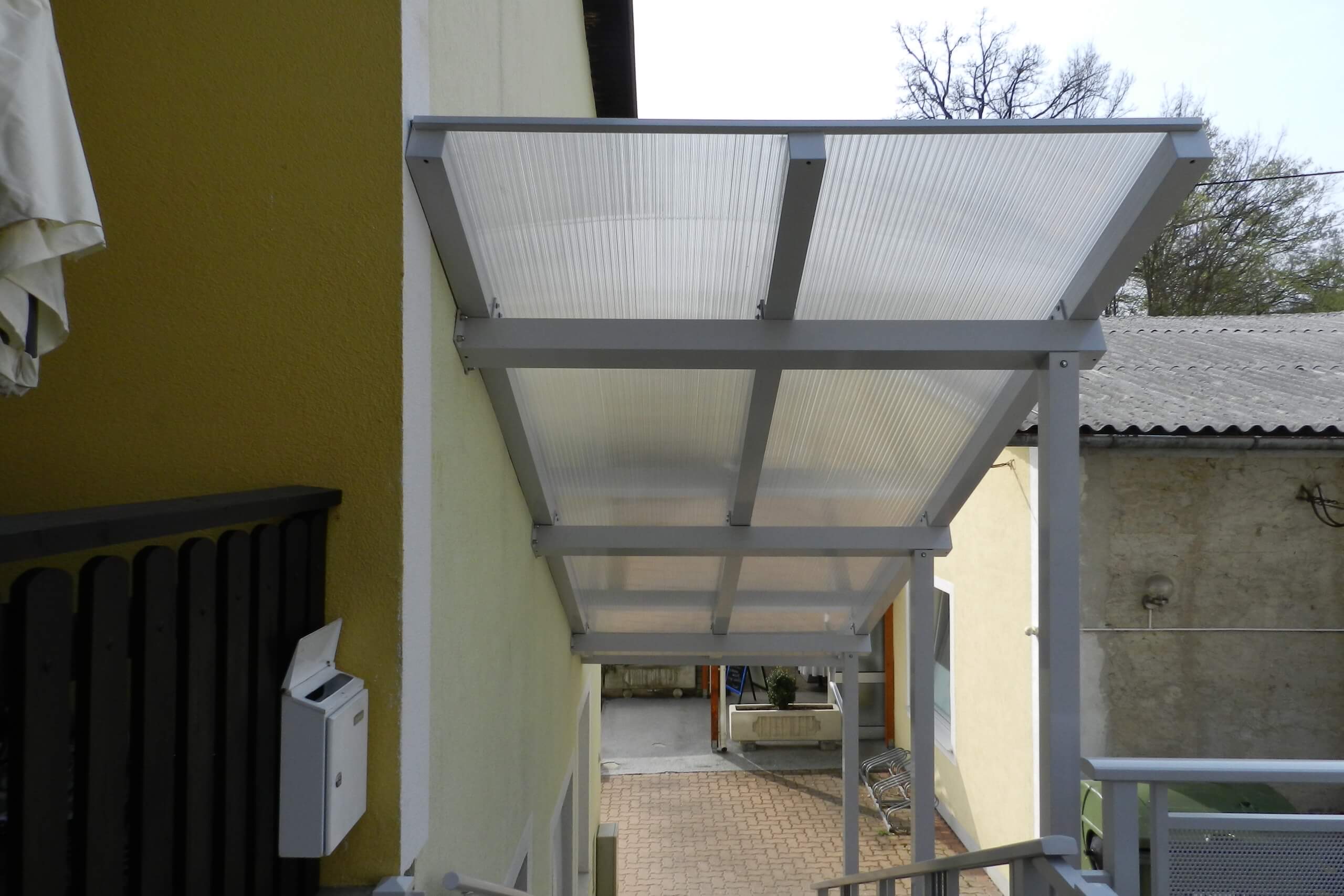 Weißes Vordach aus Metall über den Stiegen